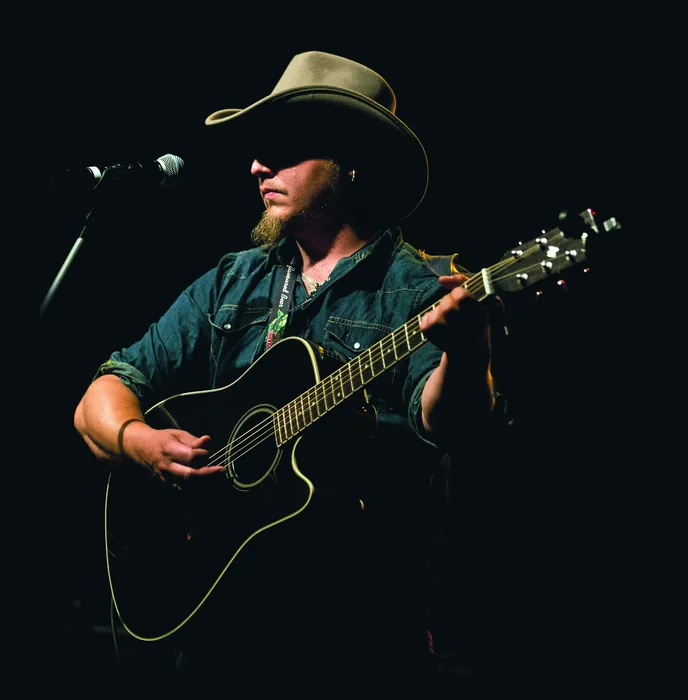 Roman Hofbauer mit Akustikgitarre auf der Bühne, Foto Klaus Biella
